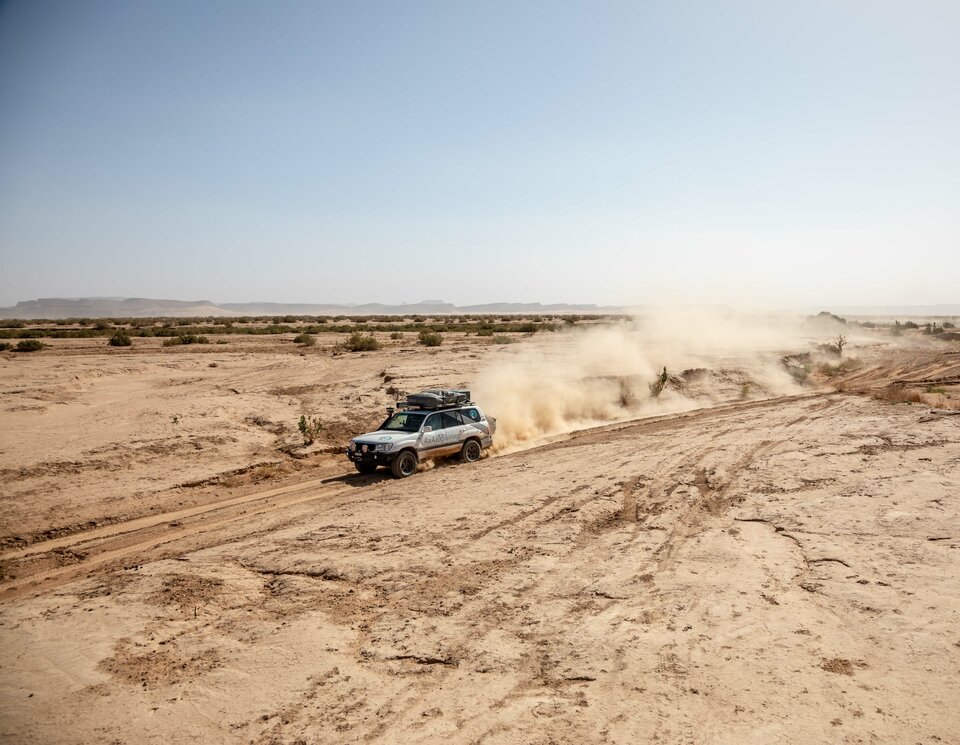 Ein Allradfahrzeug durchquert Wüste und wirbelt den Sand auf. Offroad Marokko | © 4x4 Exploring GmbH