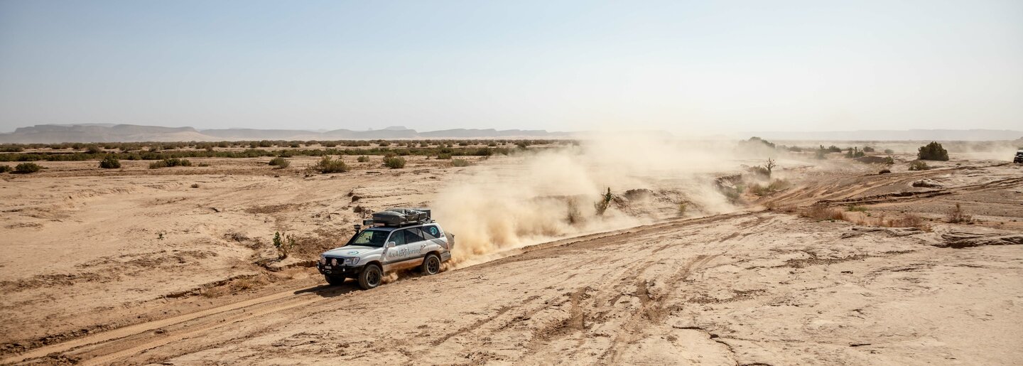 Ein Allradfahrzeug durchquert Wüste und wirbelt den Sand auf. Offroad Marokko | © 4x4 Exploring GmbH