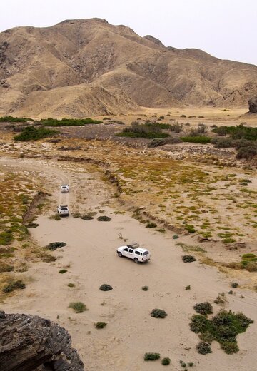 Eine Gruppe von Fahrzeugen passieren ein Bergabschnitt mit vielen Sträuchern. Offroad Namibia | © 4x4 Exploring GmbH