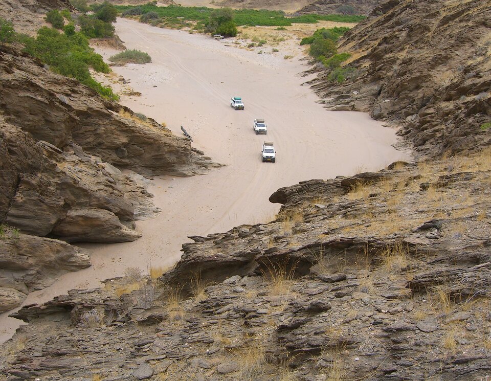 Eine Expeditionsgruppe passiert ein Flussbett, welcher in einen Canyon mündet. Offroad Namibia  | © 4x4 Exploring GmbH