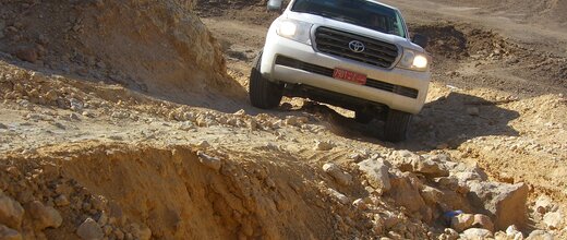 Ein Allradfahrzeug passiert ein felsigen Abschnitt der an einem Abgrund vorbei führt. Offroad Oman | © 4x4 Exploring GmbH