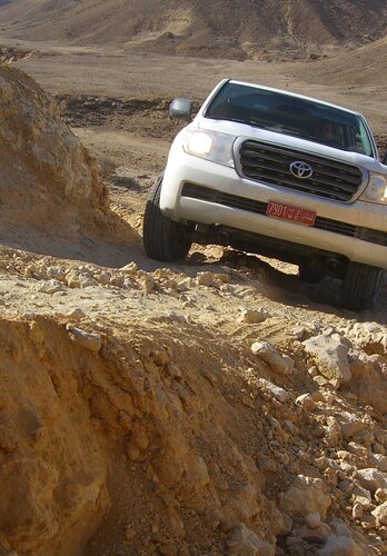 Ein Allradfahrzeug passiert ein felsigen Abschnitt der an einem Abgrund vorbei führt. Offroad Oman | © 4x4 Exploring GmbH