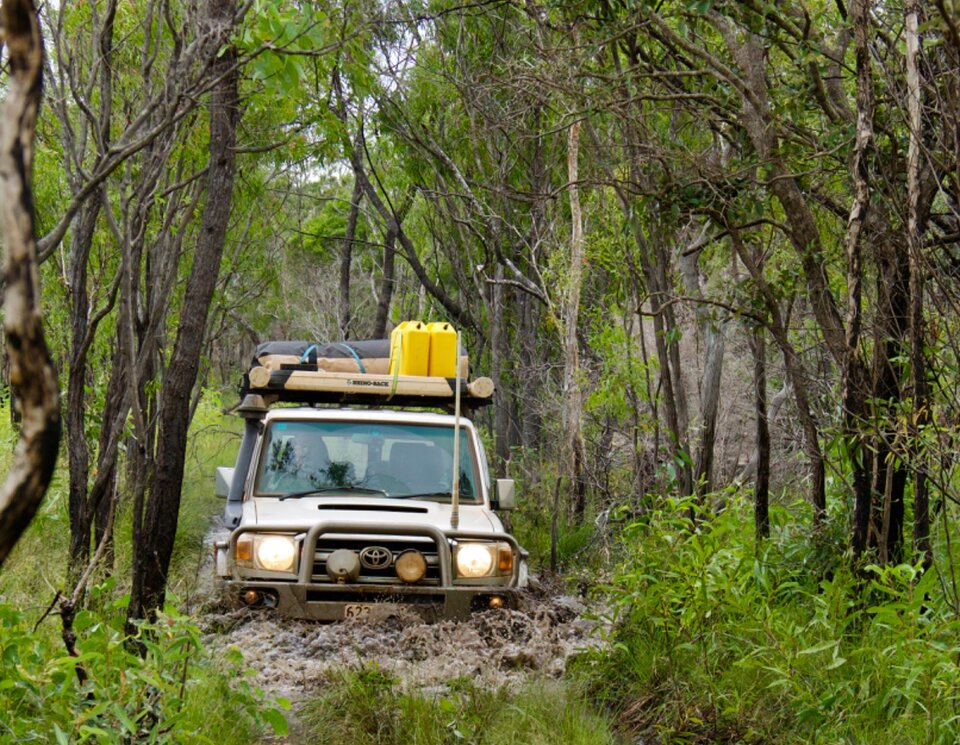 Eine schlammige Durchfahrt mit Allradfahrzeug. Das Fahrzeug schiebt eine Schlammflut vor sich hin. Offroad Cape York Australien | © 4x4 Exploring GmbH